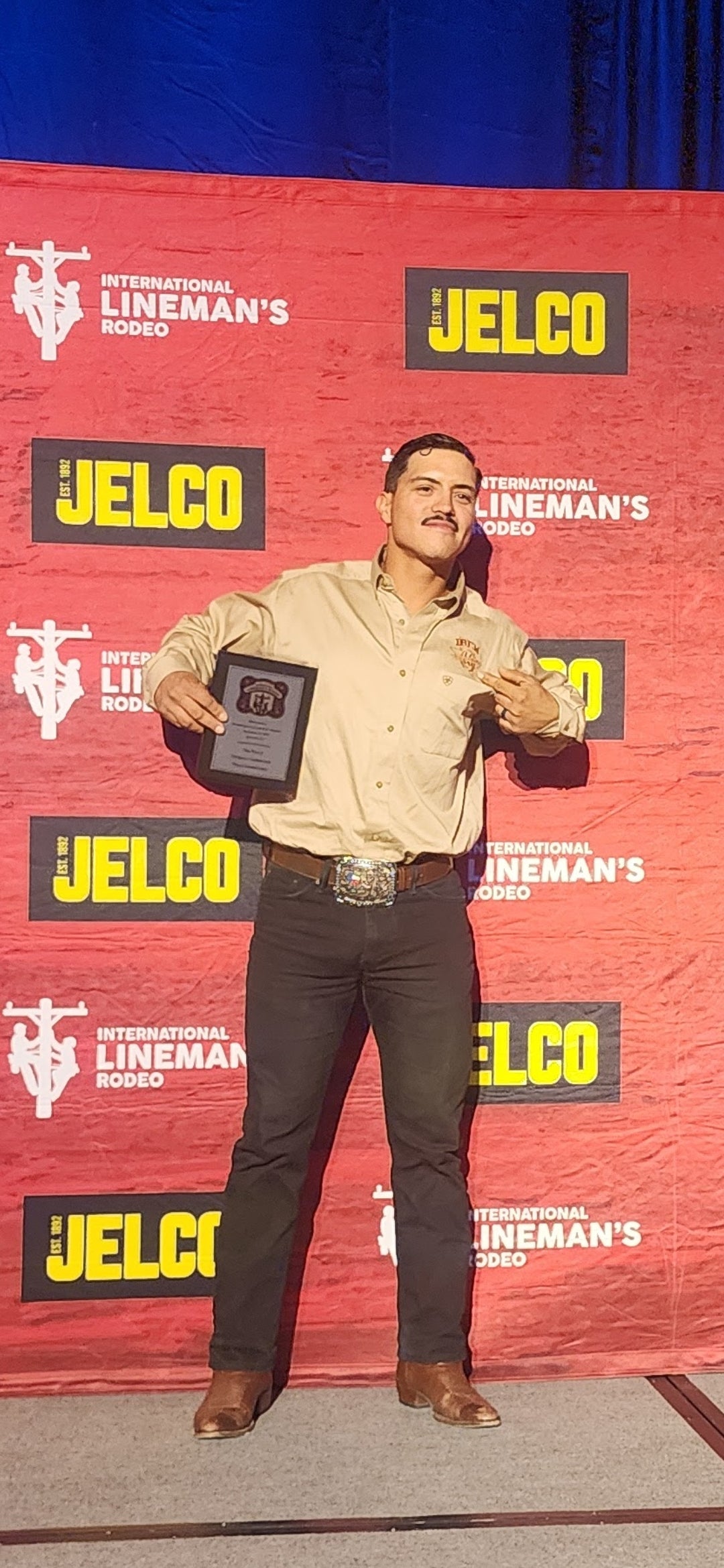 Jude Jolma sitting in an office wearing a beige electrical company shirt and cap