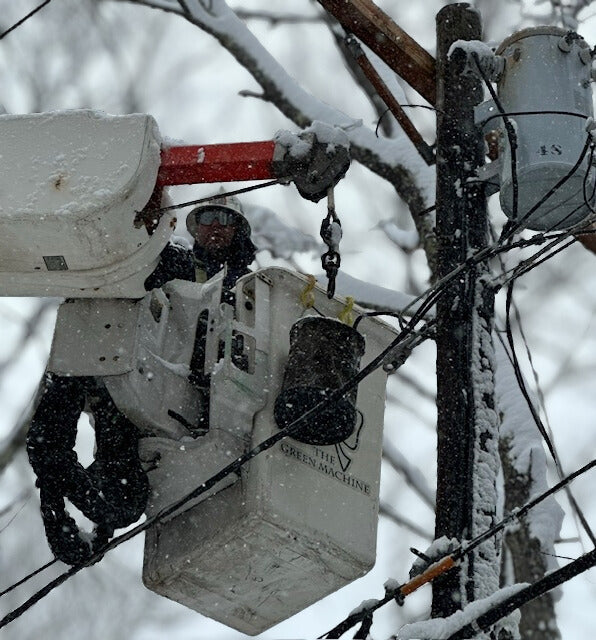 Sammy Micco working from a bucket truck in snowy conditions, maintaining power lines and ensuring electrical reliability during winter weather.