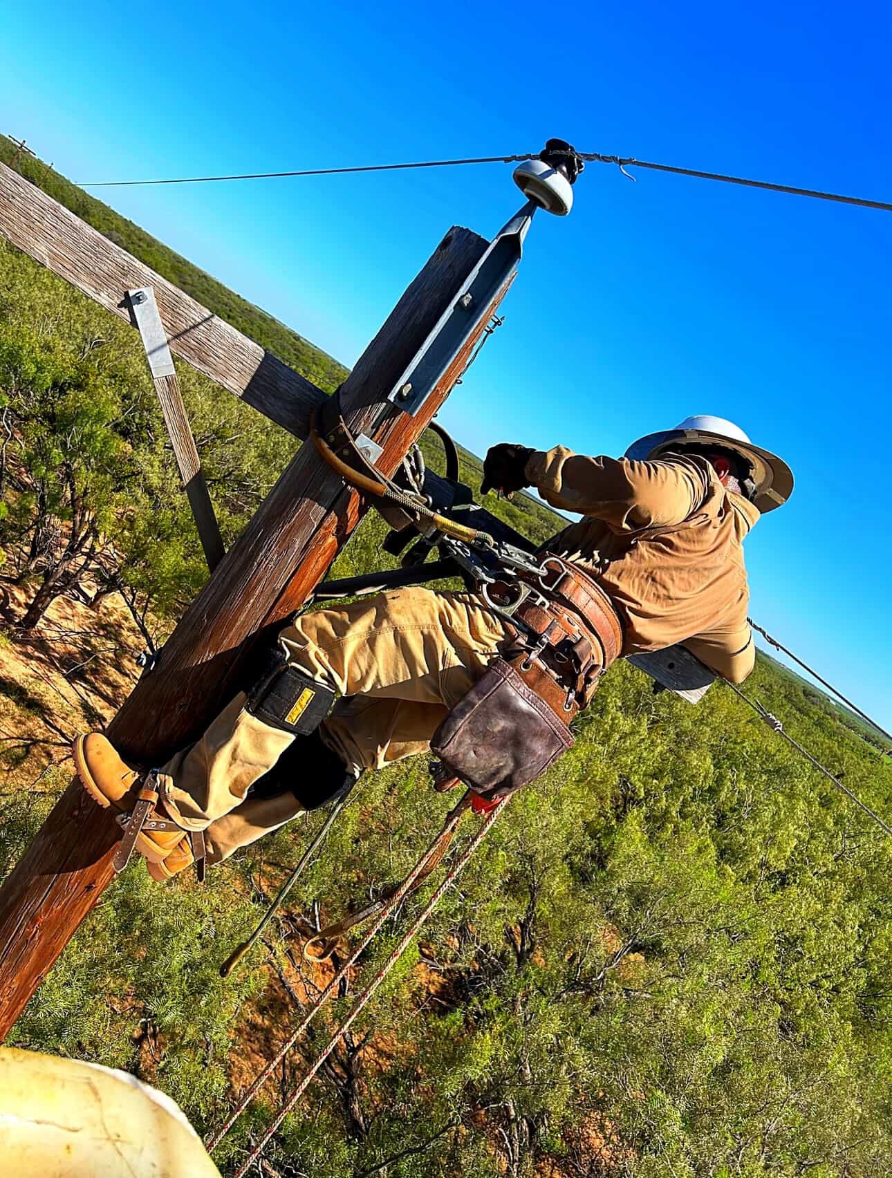 Johnny Garcia and a fellow lineman performing high-voltage line repairs from a bucket truck