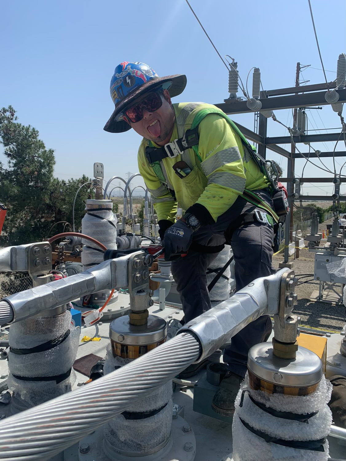Jude Jolma sitting in an office wearing a beige electrical company shirt and cap