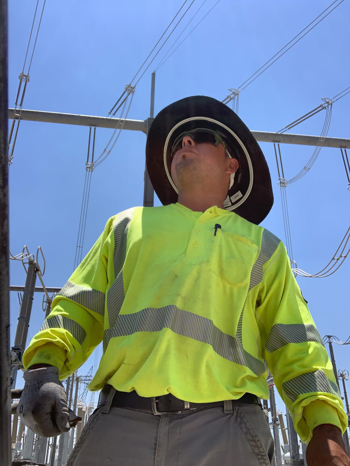 Jude Jolma sitting in an office wearing a beige electrical company shirt and cap