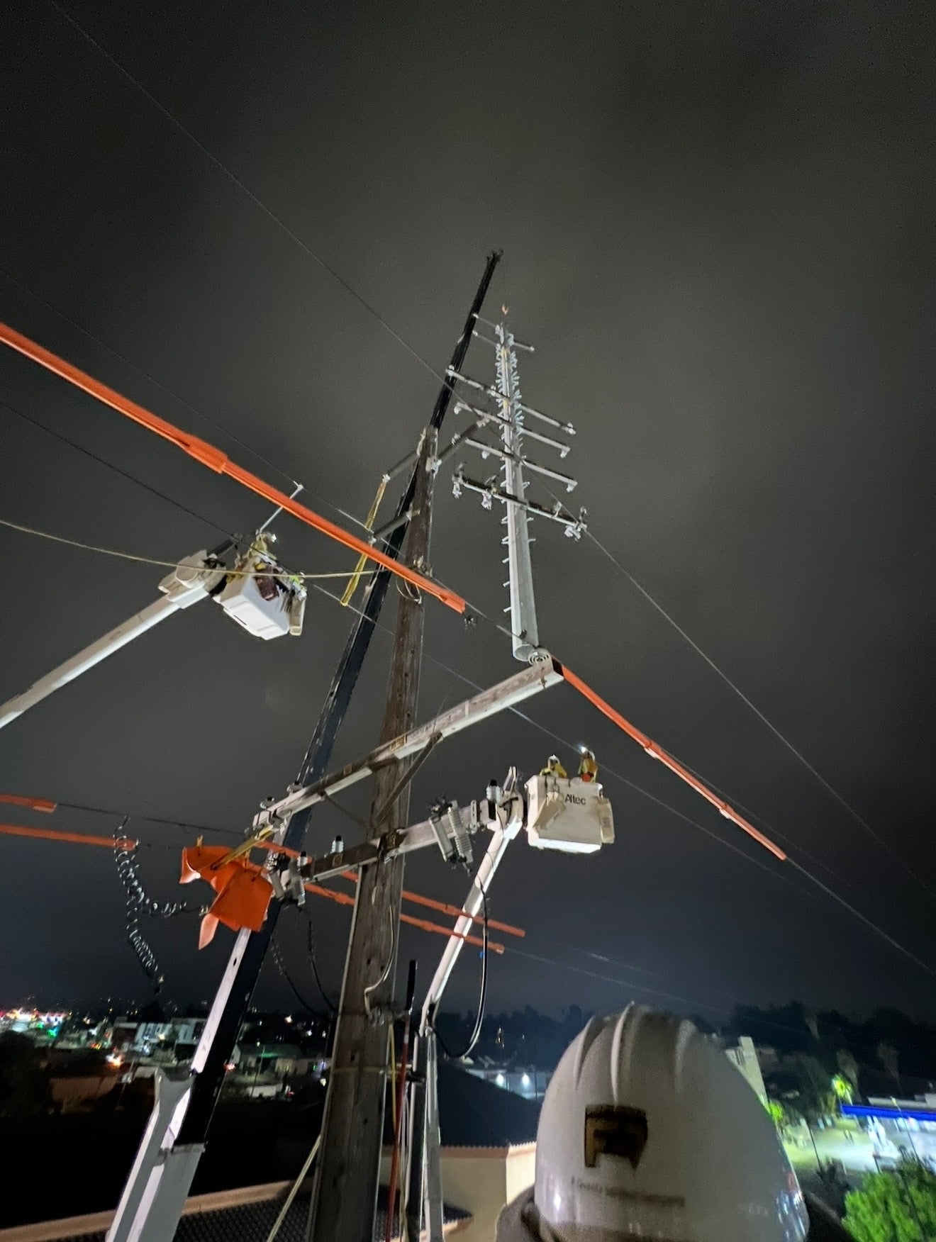 Jude Jolma wearing safety gear standing beside a large split tree in a dense forest after storm damage.
