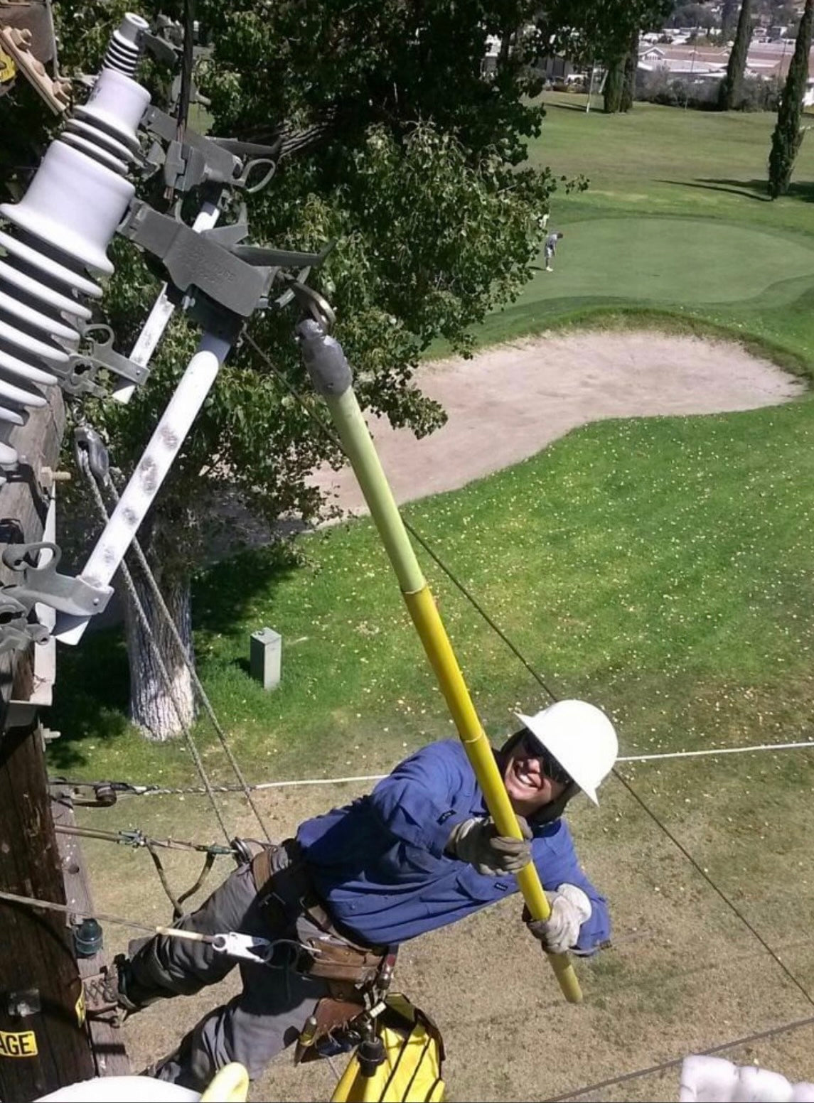 Jude Jolma standing high on a utility pole, overseeing electrical line work