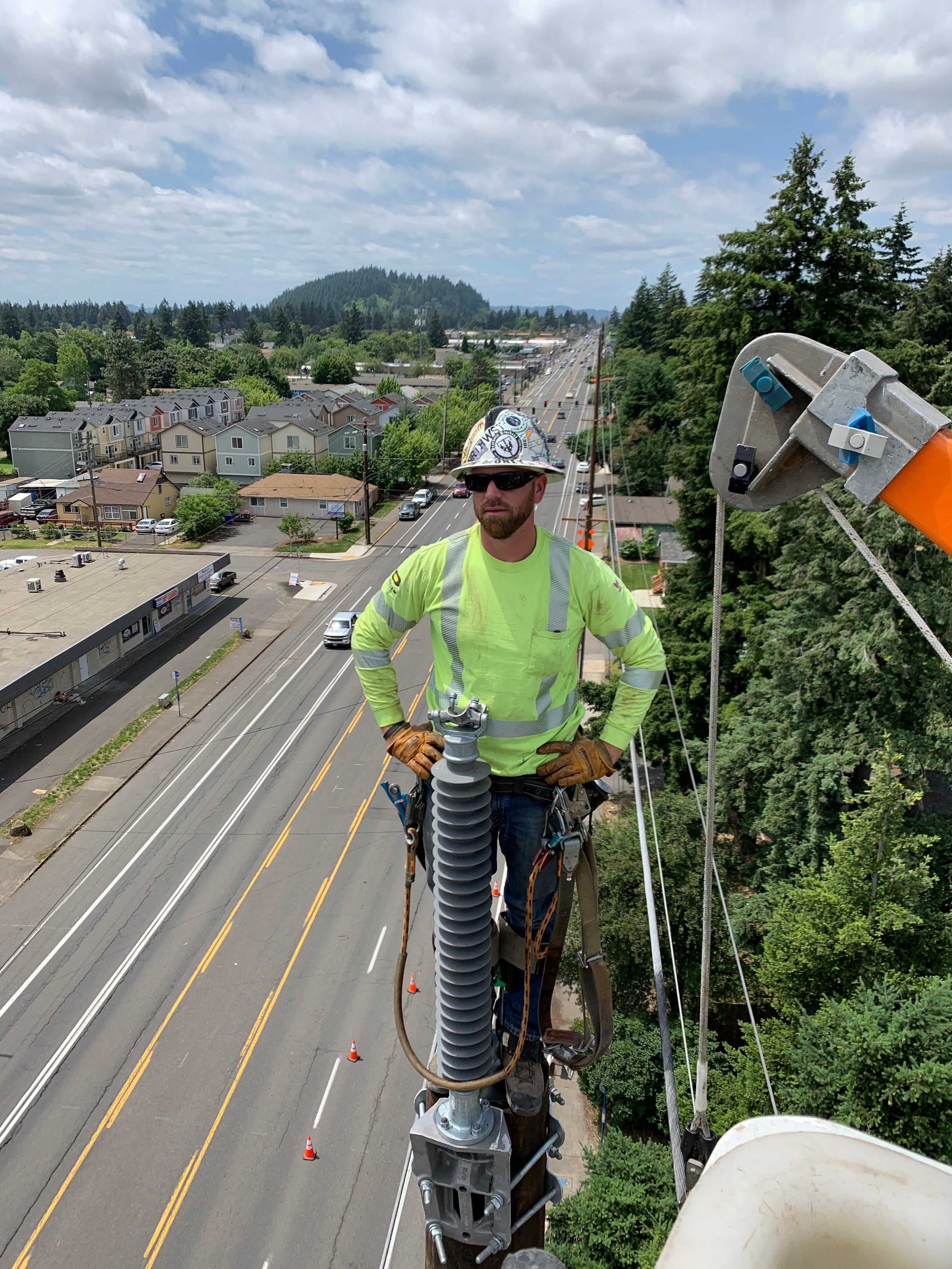 Jude Jolma standing high on a utility pole, overseeing electrical line work