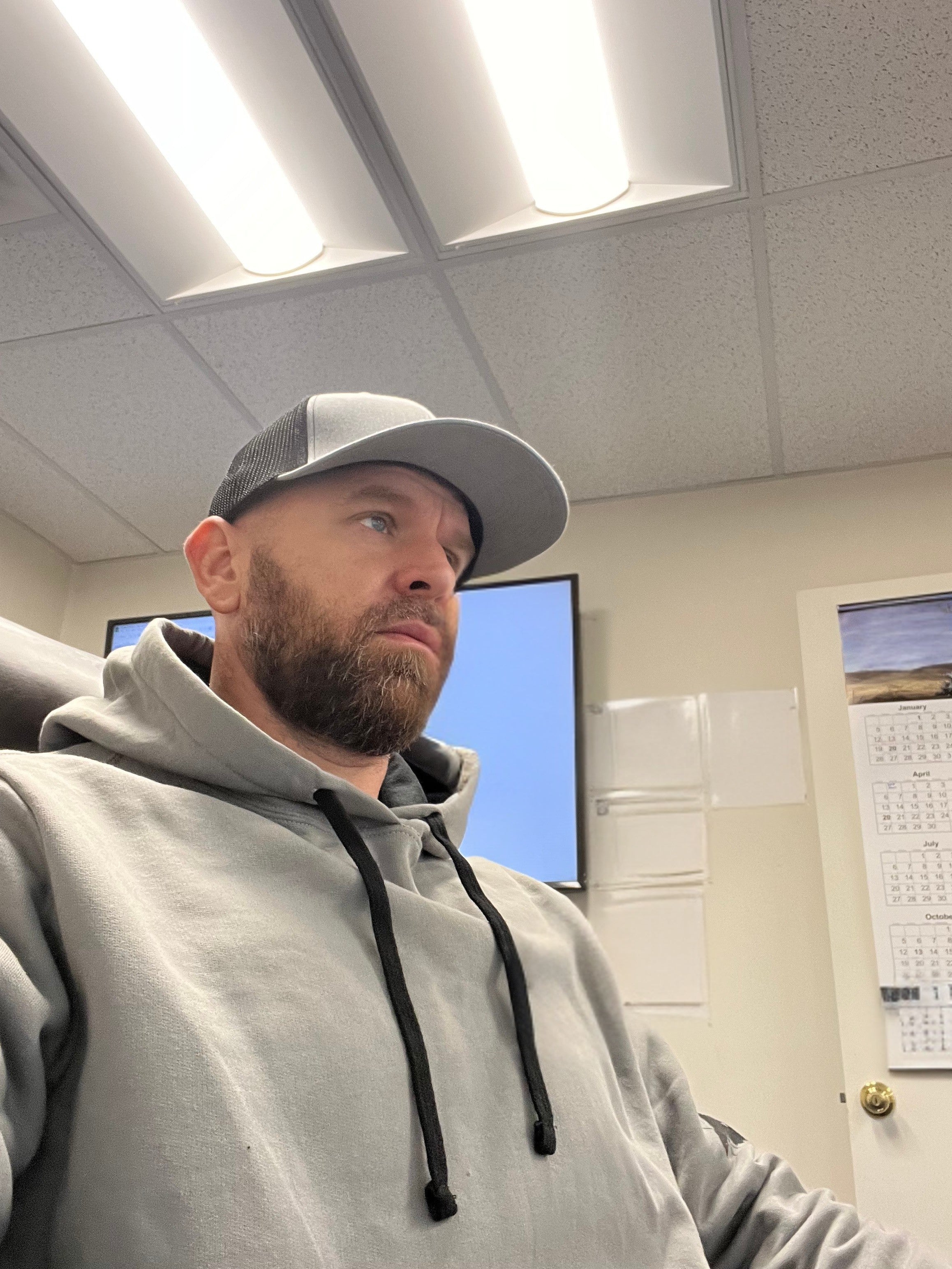 Jude Jolma sitting in an office wearing a beige electrical company shirt and cap