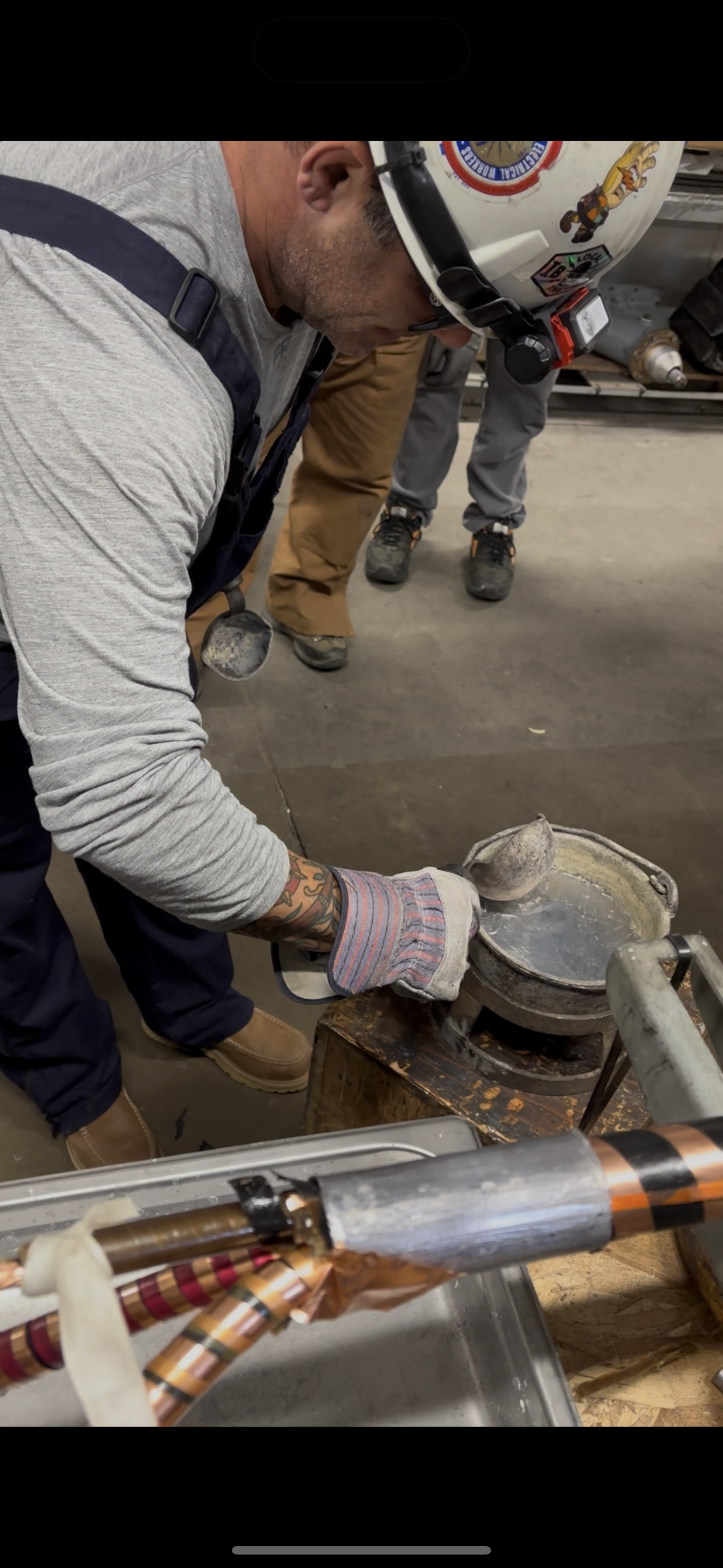 Mark Savage pouring molten metal to complete a high-voltage cable splice, demonstrating precision and skill in underground power work