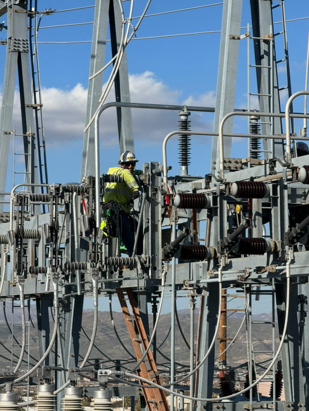 Substation electrician performing maintenance on high-voltage electrical substation equipment