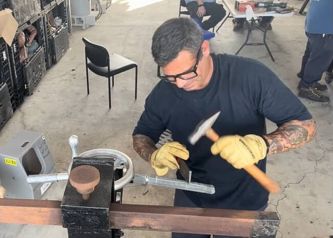 Mark Savage shaping a high-voltage cable connection with a hammer during underground splicing preparation