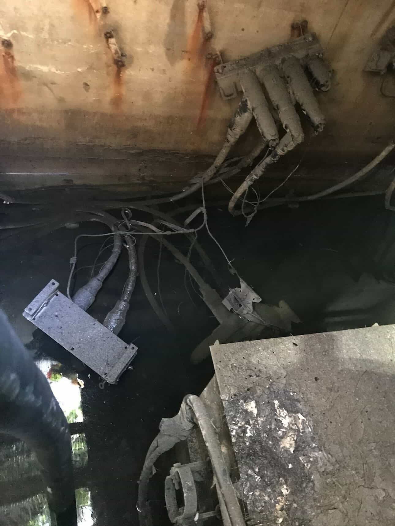 Water-damaged underground electrical vault with submerged high-voltage cables, showing the harsh conditions faced in power maintenance work