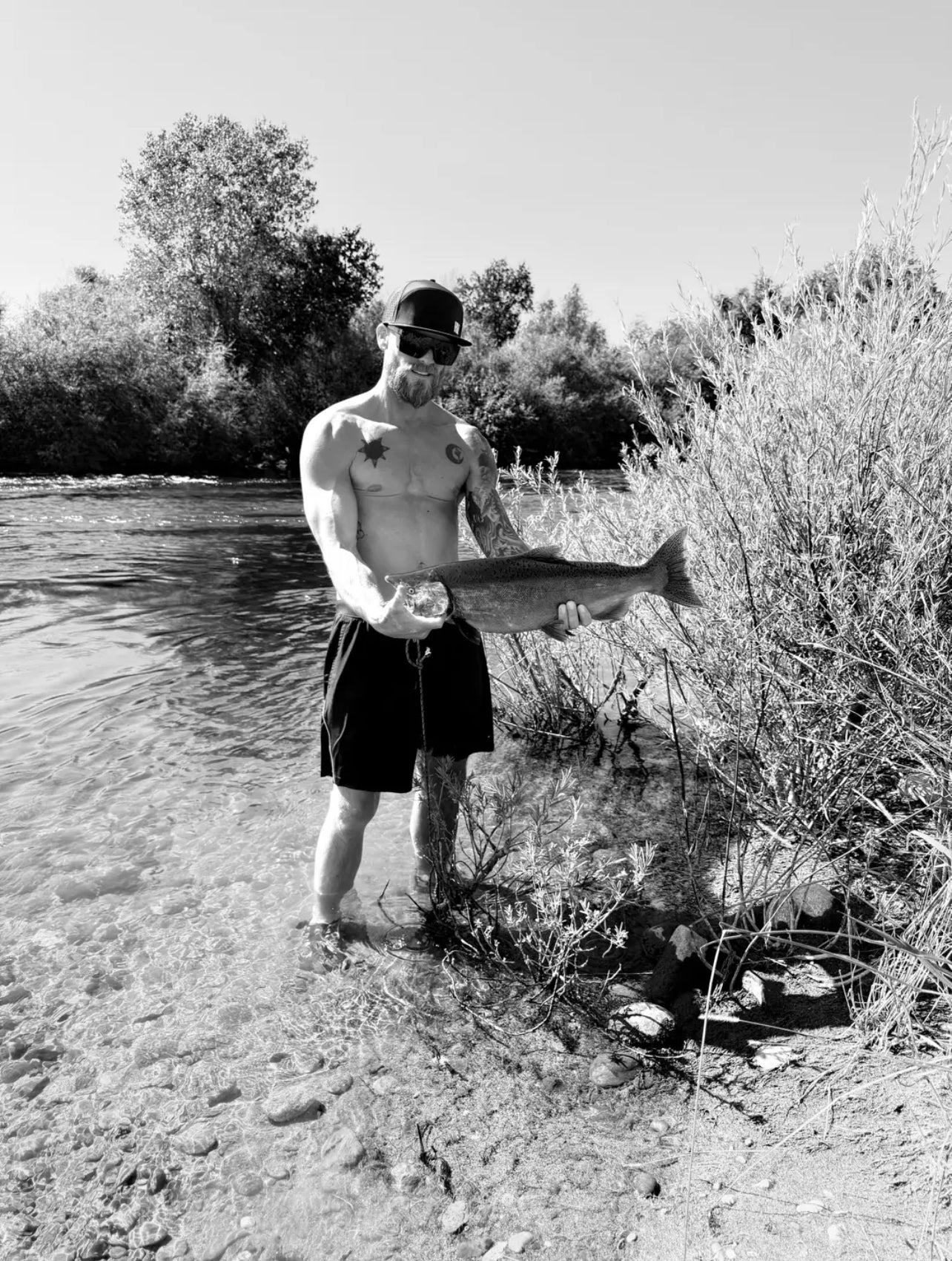 Collin Birkholz proudly holds a large fish while standing in a river.