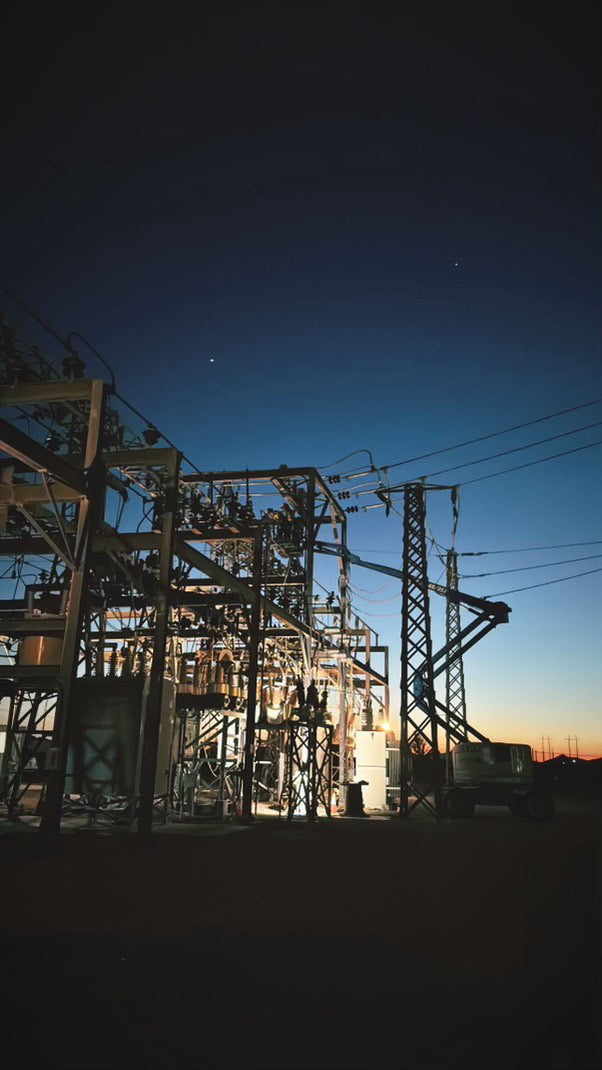 High-voltage electrical substation with transmission lines and steel structures at dusk