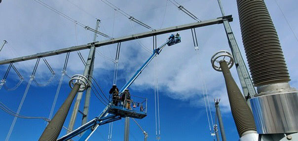 Substation workers on aerial lift installing or maintaining high-voltage equipment at electrical substation