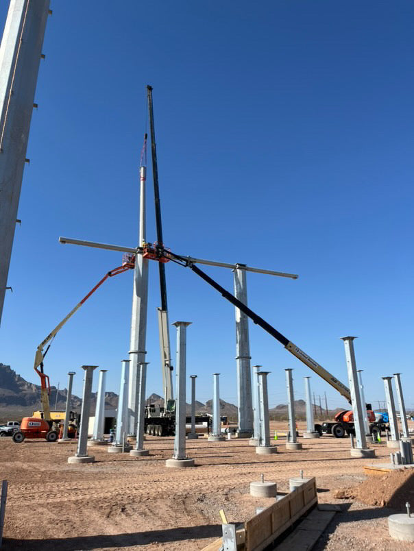 Construction cranes lifting and installing steel structures at a high-voltage electrical substation site