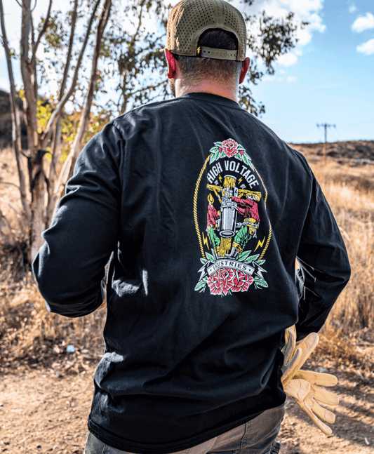 Person wearing a black long-sleeve shirt with a colorful graphic design on the back, standing outdoors.