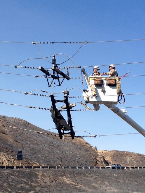 Johnny Garcia and a fellow lineman performing high-voltage line repairs from a bucket truck